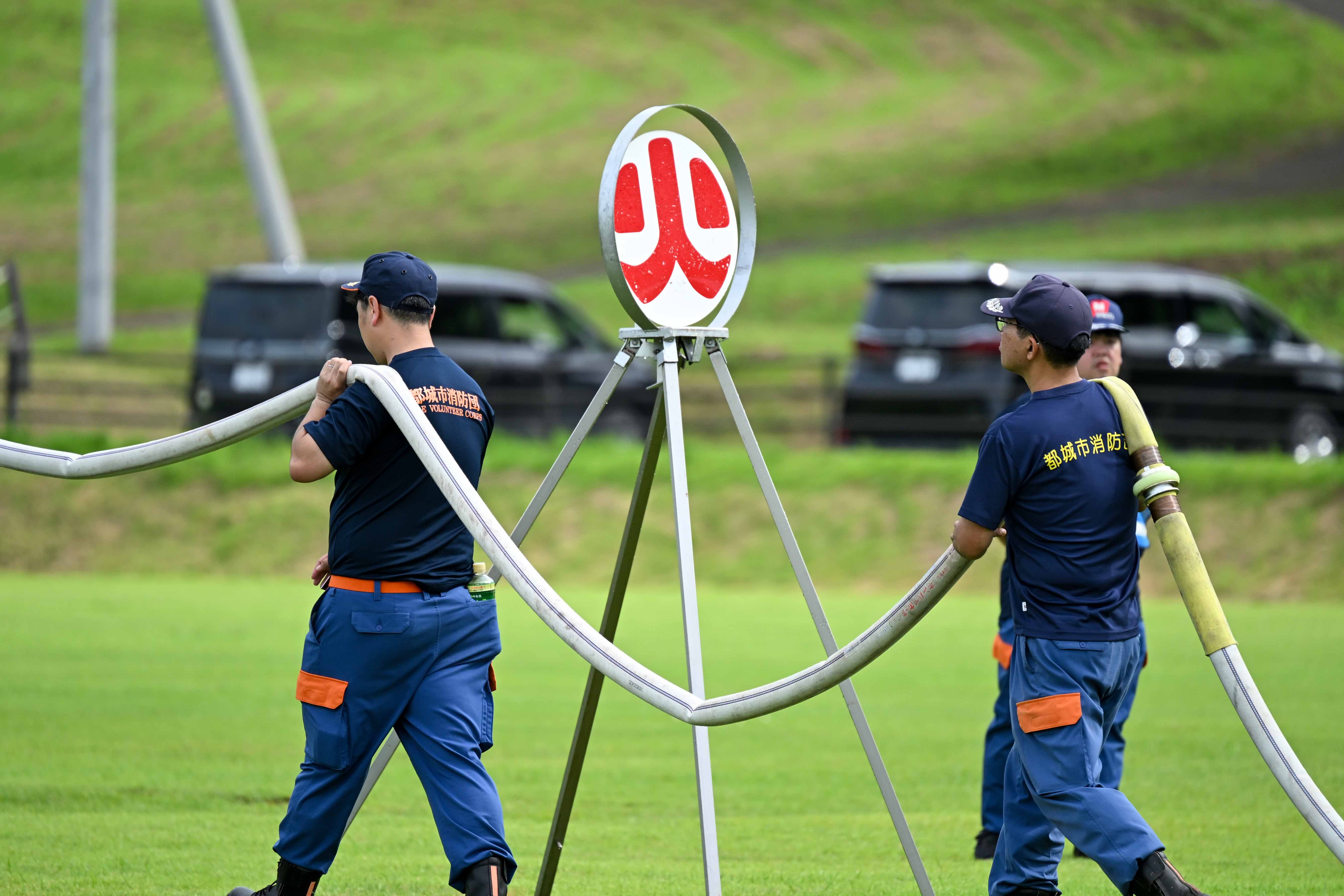 ホースを担ぐ2人の消防団員