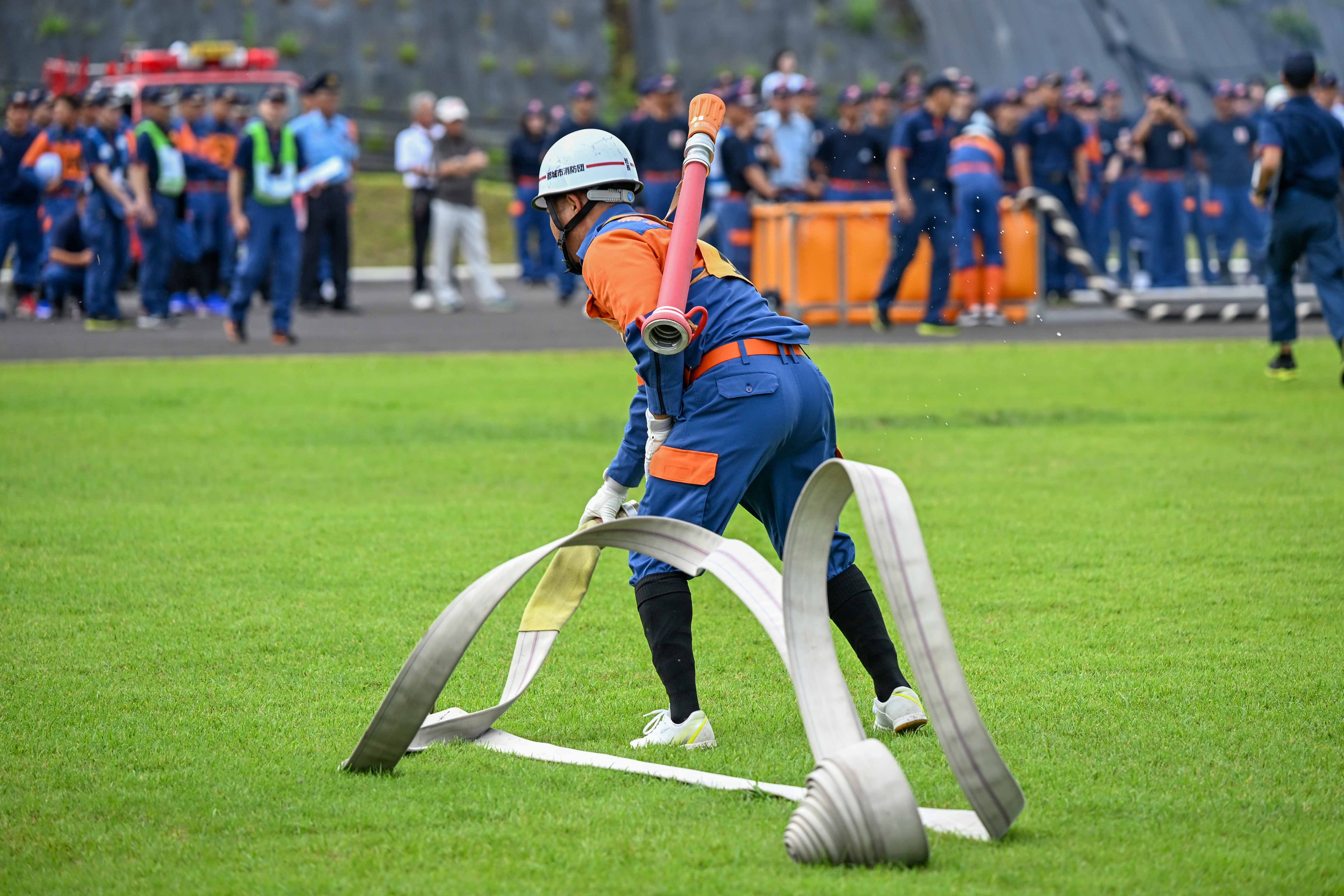 ホースを伸ばす消防団員の後ろ姿